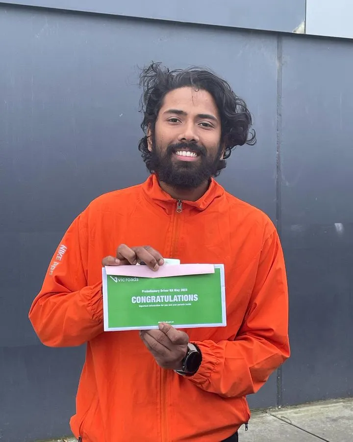 Man in an orange jacket holding a green certificate that says "CONGRATULATIONS